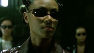 Jada Pinkett Smith gives a briefing while wearing sunglasses in The Matrix Reloaded.