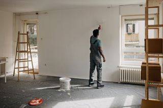 man in a room painting the walls white
