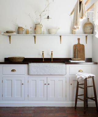 white small shaker kitchen with dark iroko wood countertops and a terracotta floor