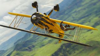 Tom Cruise hangs from the wing of a yellow propeller plane in Mission: Impossible - The Final Reckoning