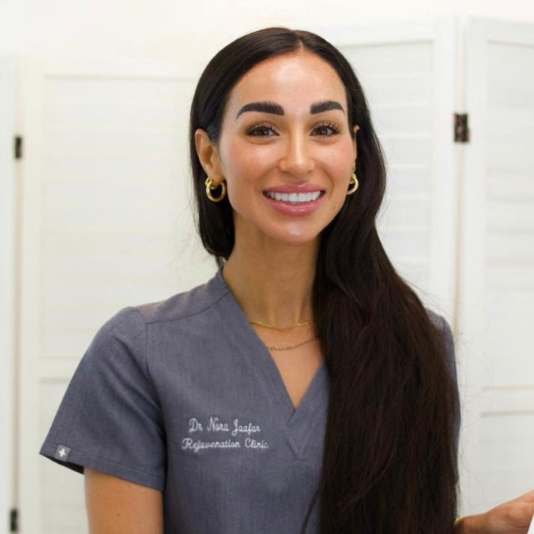 Dr Nora Jaafar smiling with long brunette hair over one shoulder and wearing a grey uniform