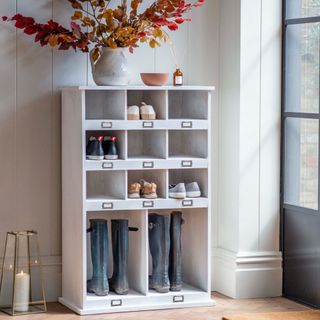 hallway with wooden shoe storage unit that holds shoes, wellies, vase of foliage on top