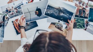 A person looks over printed photographs on a table