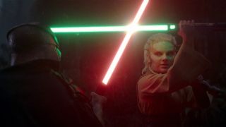 A jedi wielding a green lightsaber blocks the strike from a red lightsaber held by the masked villiain.