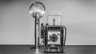 A Graflex Speed Graphic camera, with flash.