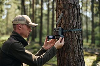 an individual setting up the Zeiss Secacam 3 outdoors on a tree in a forrest