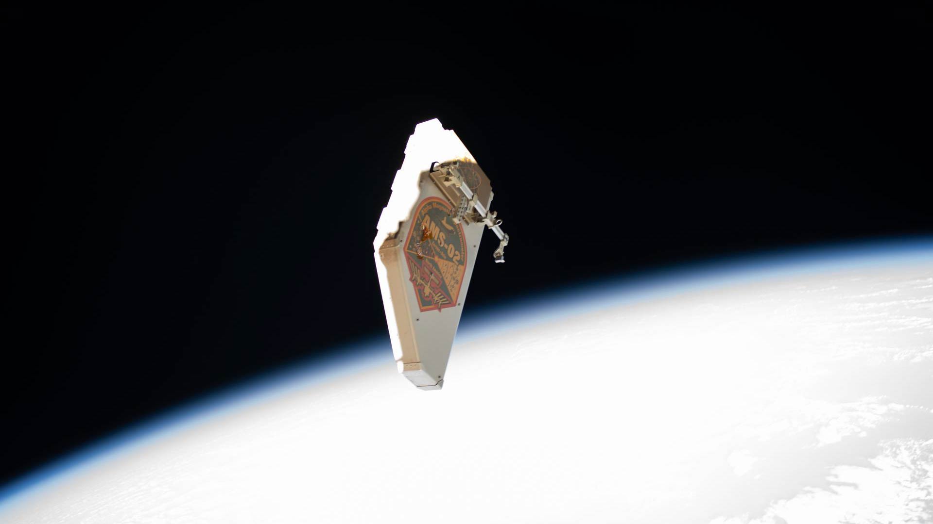 A debris shield that was removed from the Alpha Magnetic Spectrometer (AMS), the International Space Station's cosmic particle detector, is pictured drifting away from the orbiting lab.