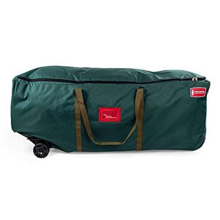 A green fabric tree storage bag with green fabric handles. A red label slot on the front and black wheels on the bottom left. 