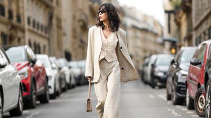 woman wearing a cream linen suit of a linen blazer, linen pants, and linen vest.