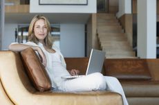 Woman relaxing on a couch in her loft with a laptop on her lap