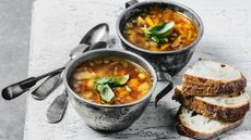 Chunky vegetable soup in metal cups with crusty bread