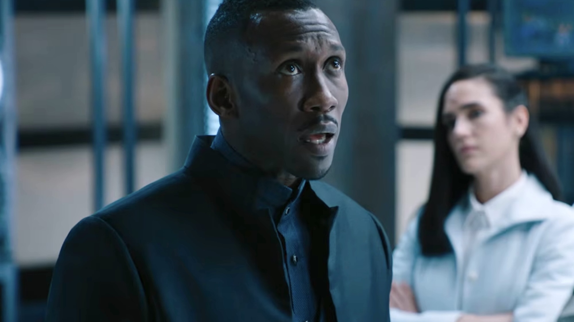 Mahershala Ali in a black coat looking up in the trailer for Alita: Battle Angel. 