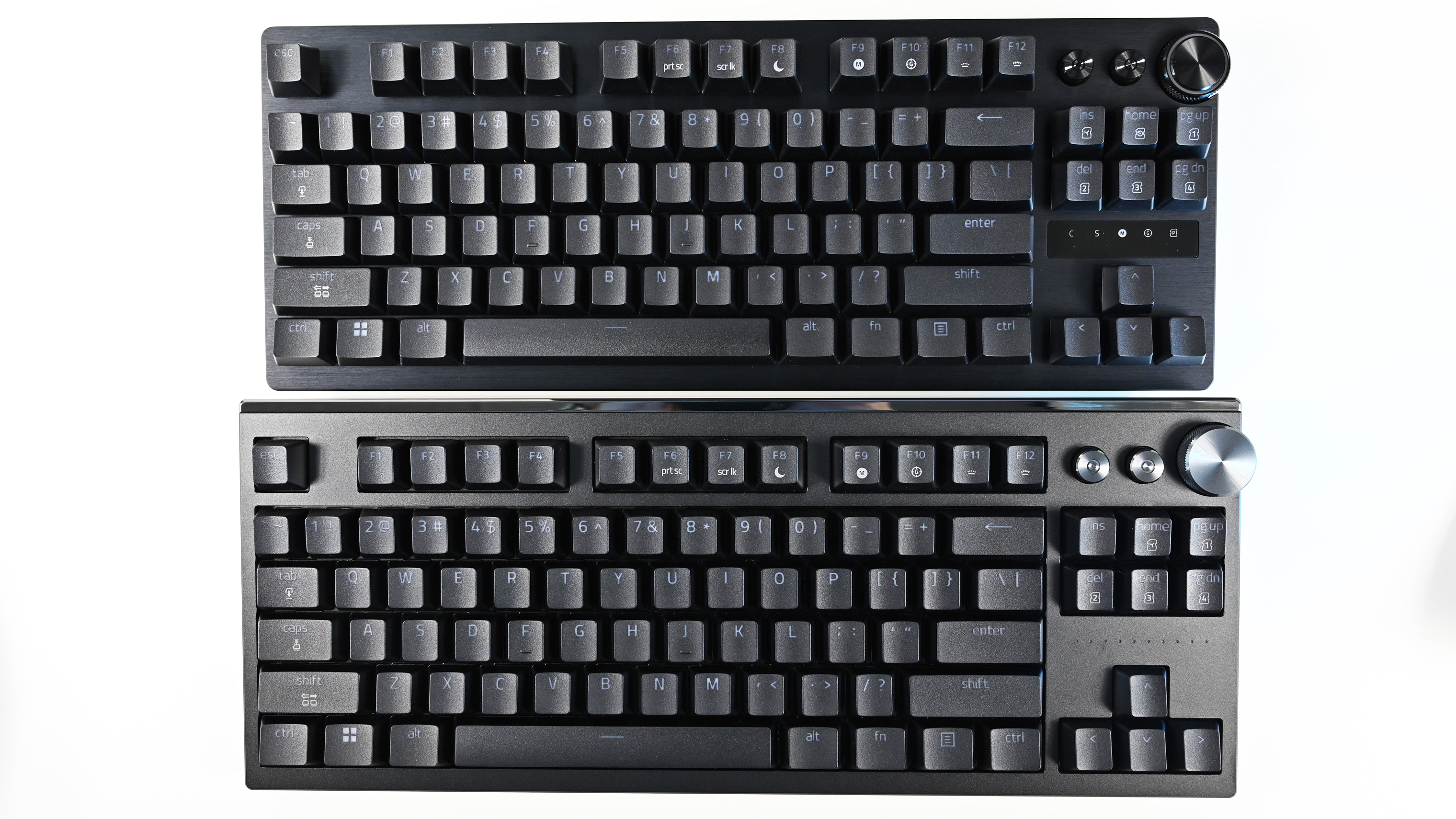 Top-down comparison view of two similar Razer mechanical keyboards stacked vertically, highlighting slight structural and knob design differences.