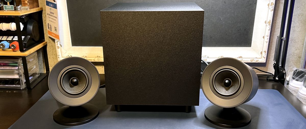 Razer Nommo V2 speakers on desk with subwoofer.