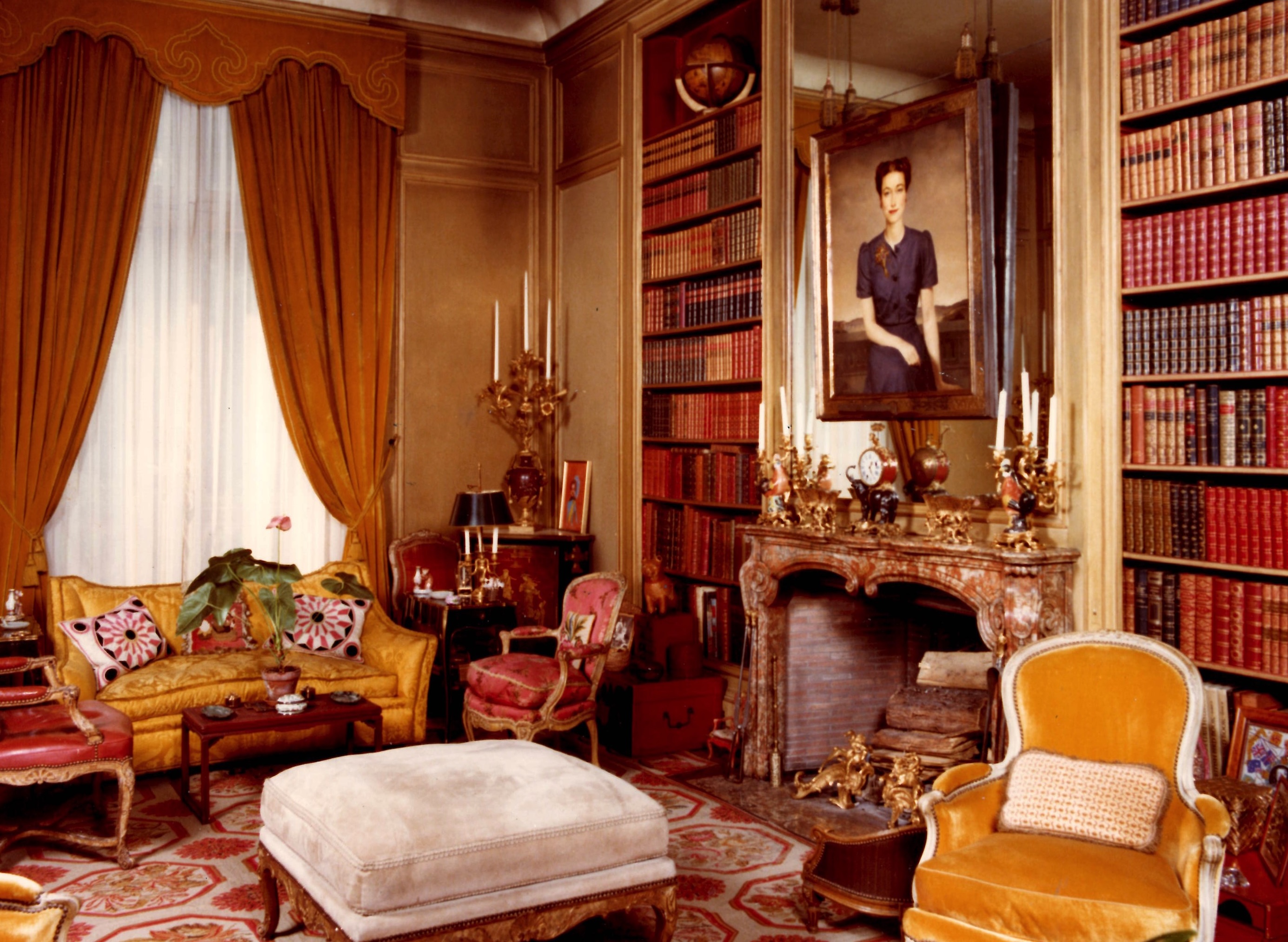 Ornate library with yellow curtains and upholstery and a portrait of the Duchess of Windsor over the mantelpiece