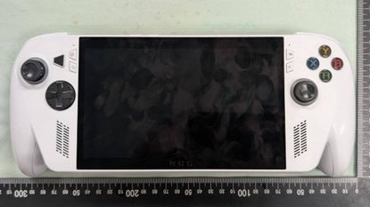 White Xbox handheld sitting on light green surface next to ruler.