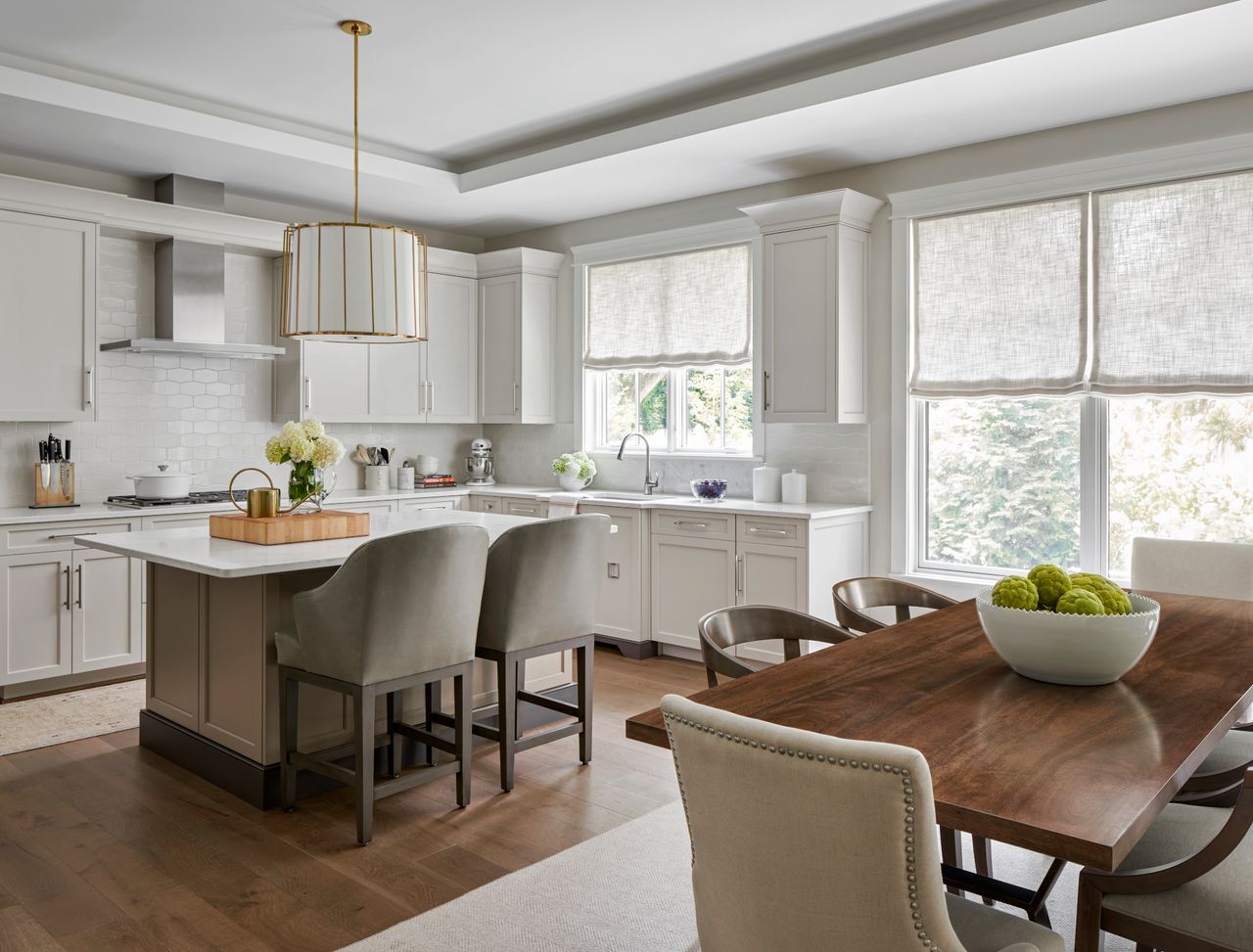 white kitchen with island, bar stools, wooden table and chairs
