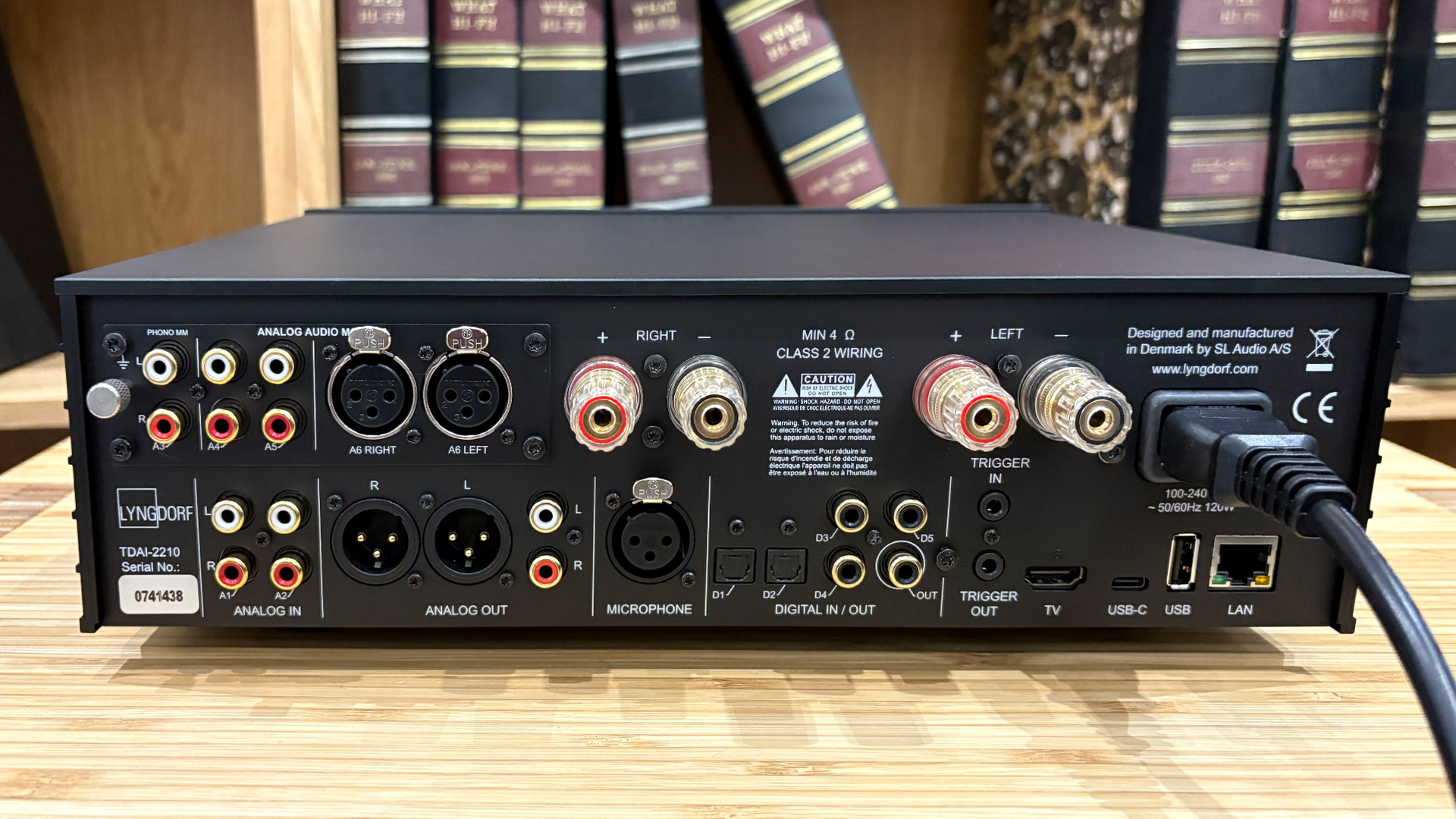Lyngdorf TDAI-2210 streaming amplifier on wooden hi-fi rack in front of bookcase rear of unit showing connections