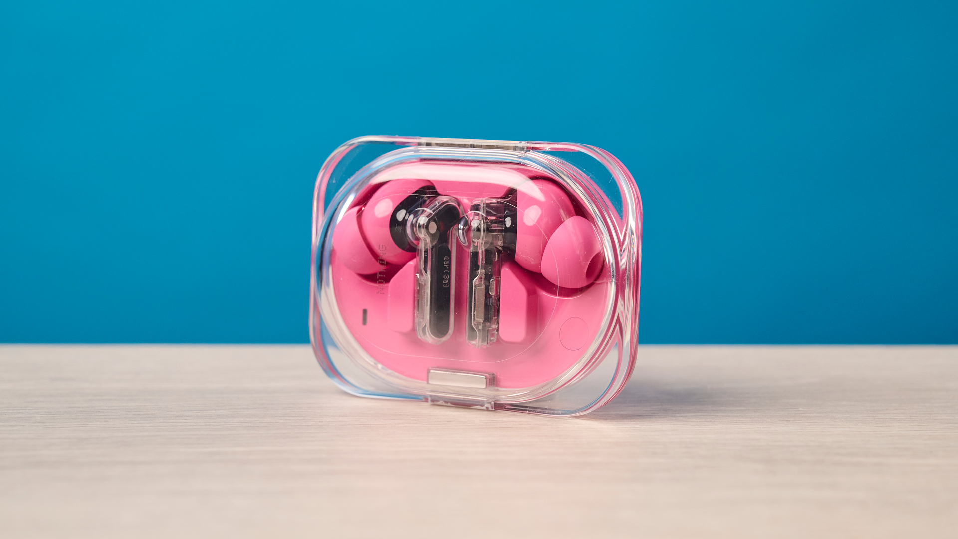 The Nothing Earbuds (3a) in pink, on a wooden surface