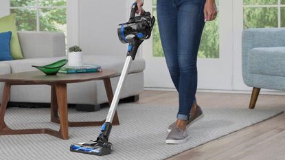 The Hoover ONEPWR Blade+ on a carpet, being pushed by a woman