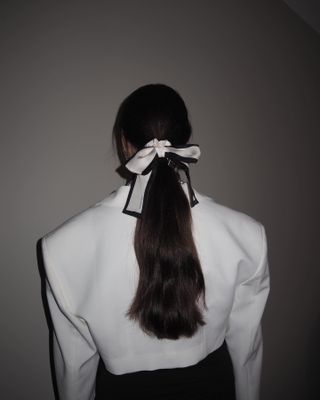 a woman with a long ponytail and bow hair accessory