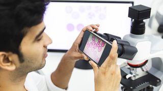 man photographing microscope specimen with a phone