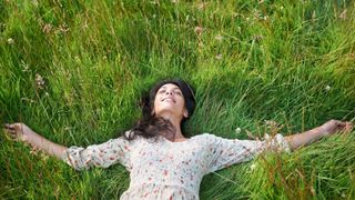 Sounds for mental health, Woman lying outside in field enjoying nature