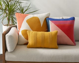 An assortment of color blocked and floral indoor outdoor cushions