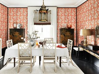Dining room with orange wallpaper, white dining furniture and dark wood elsewhere