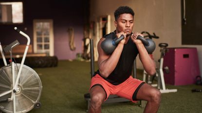 man lifting two kettlebells