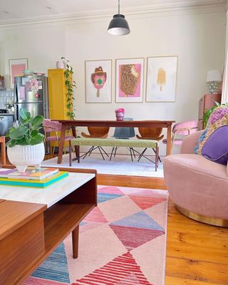 A colorful small living room with a dining table, rug, chair, and coffee table