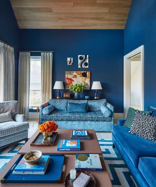 dark blue living room with various blue sofas and wood ceiling