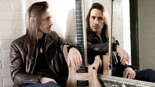 Nuno Bettencourt poses in front of a mirror with his signature Washburn electric guitar