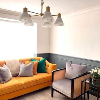 living area with white wall and wooden floor and yellow sofa