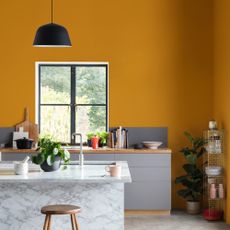 Yellow kitchen with grey cabinetry and marble island