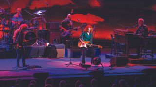 Bonnie Raitt playing guitar onstage with her live band.