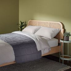wooden bed with weighted blanket and rug