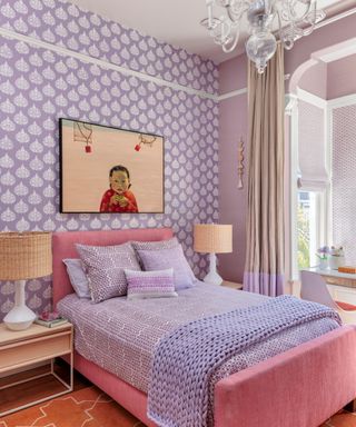 child's room with purple patterned wallpaper, purple walls and bedlinen, pink bed and chandelier
