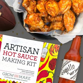 A Grow and Make artisan hot sauce kit box and a bottle of red hot sauce and chicken wings