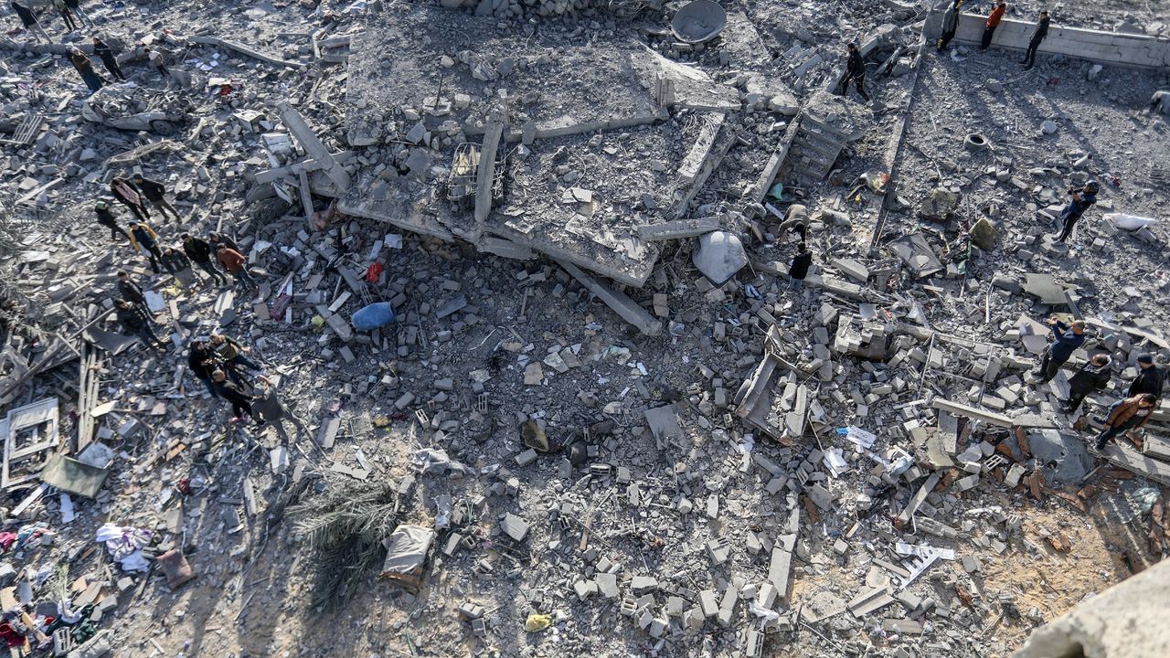 Residents inspect around the rubble of the building following an Israeli attack in Rafah, Gaza