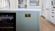 A kitchen island painted green, with a socket in brass