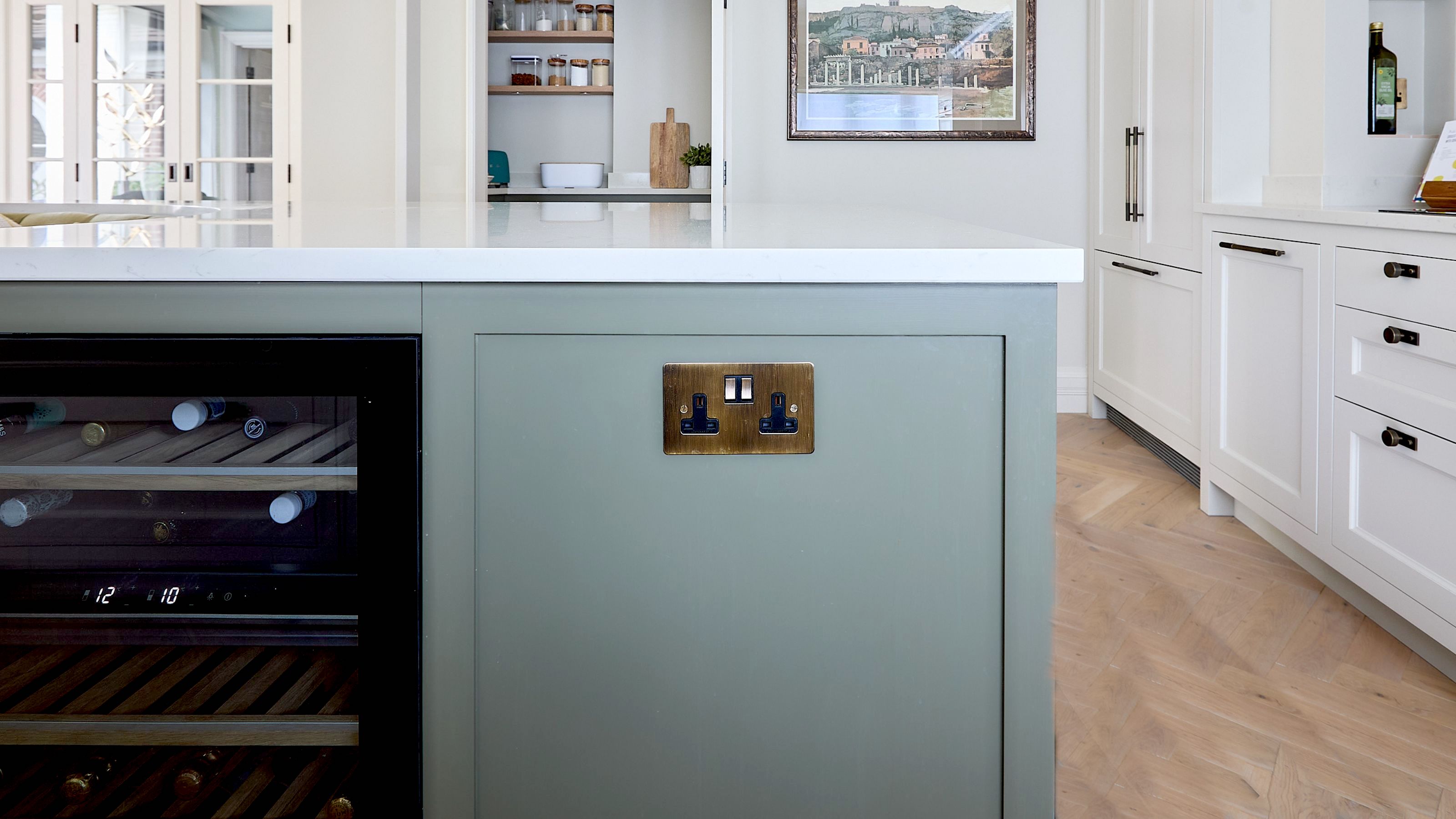 A kitchen island painted green, with a socket in brass 