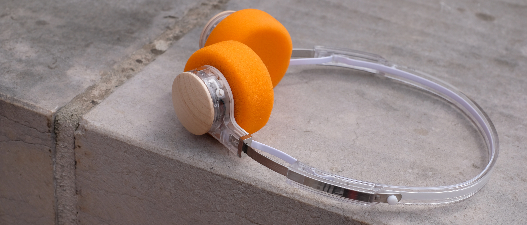 A photograph of the FiiO EH11 over-ear headphones with a transparent frame and orange foam earpads.