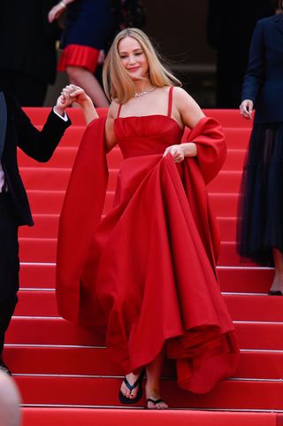 jennifer lawrence mengenakan sandal jepit dengan gaun merah di festival film cannes