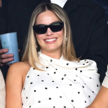 Margot Robbie in the stands at Wimbledon wearing the black and white polka dot dress trend in the form of an Alaïa dress