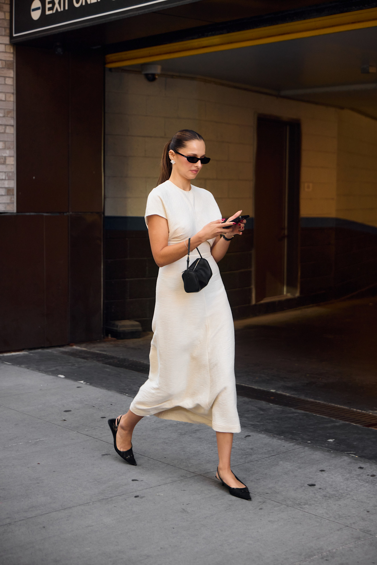 a fashion week attendee wearing sunglasses, white dress, and black flats