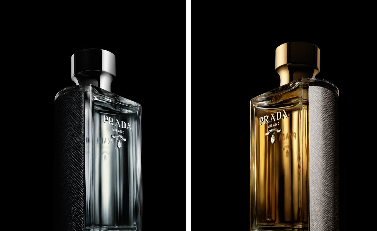 Two side-by-side photos of ’L’Homme Prada’ and ’La Femme Prada’ fragrances against a black background - one bottle has a silver cap and interior and the other bottle has a gold cap and interior