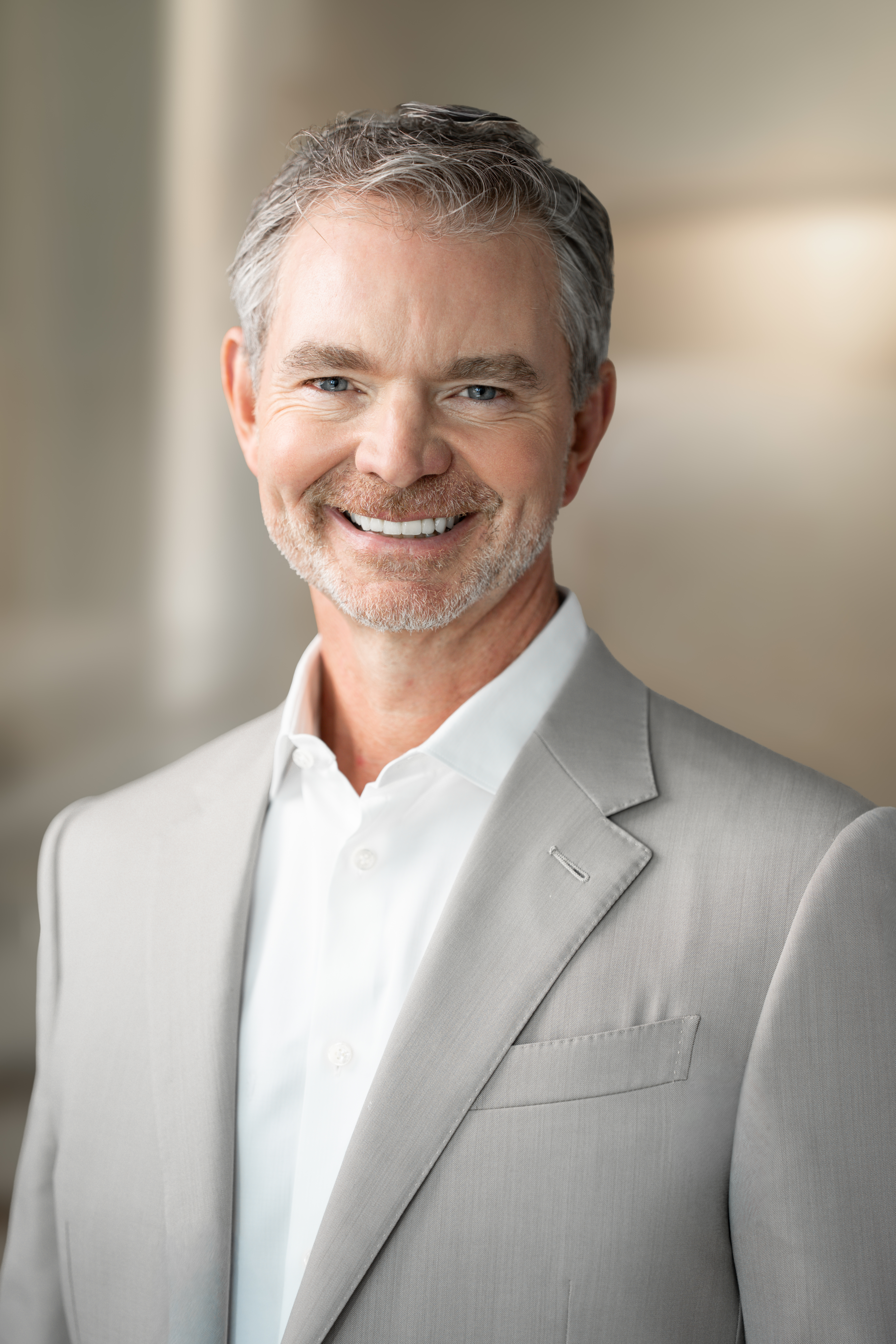 a white man with white hair in a gray suit with a white shirt
