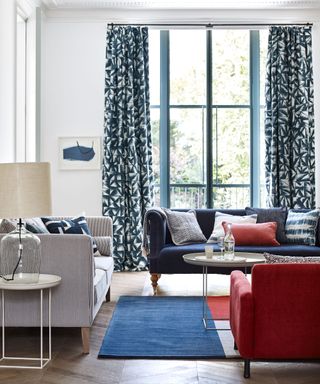 Living room with modern blue and white furnishings, and a red sofa in foreground