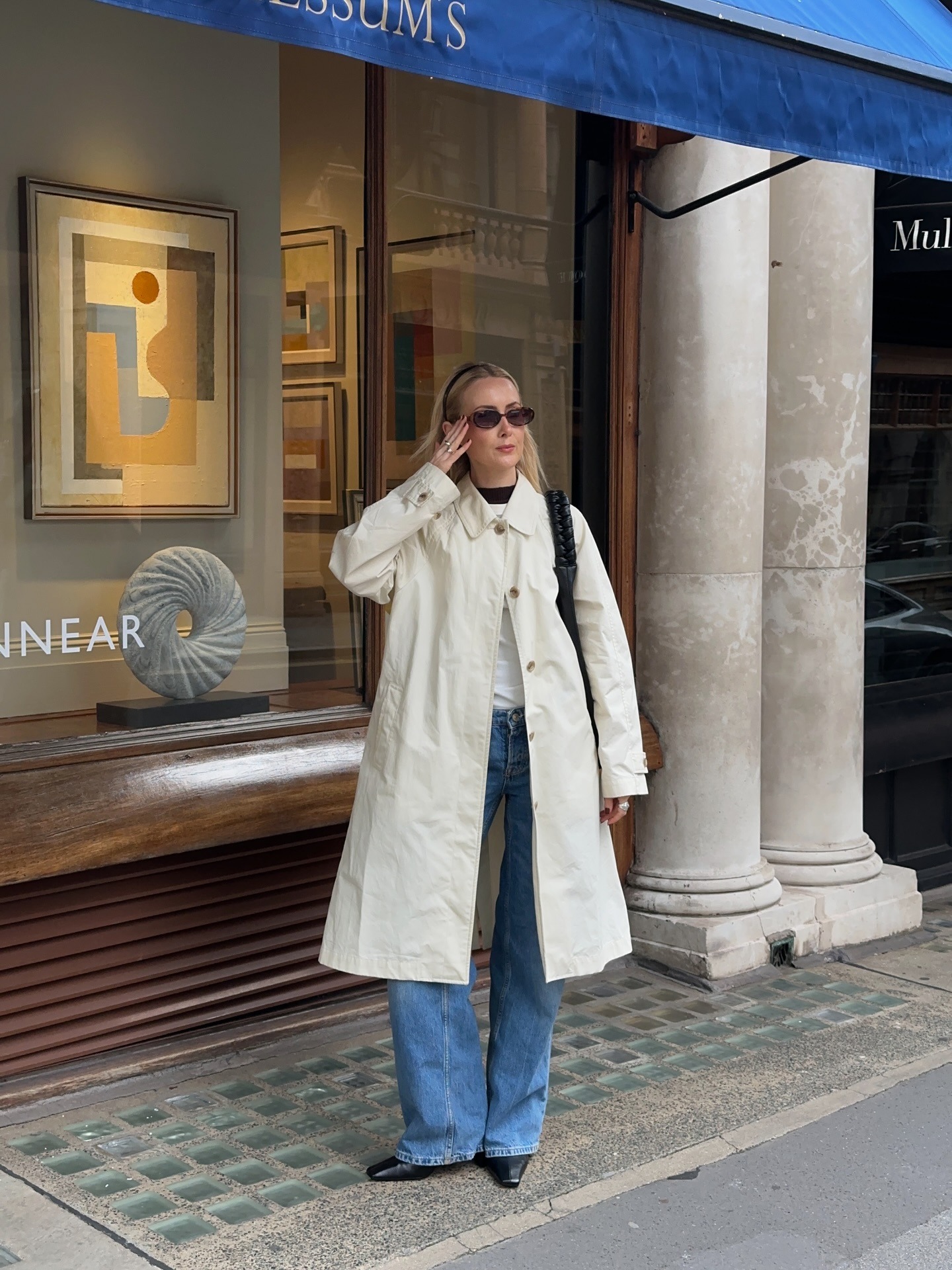 @chloekathbutler wearing a trench coat, jeans, white T-shirt, and pointed-toe boots